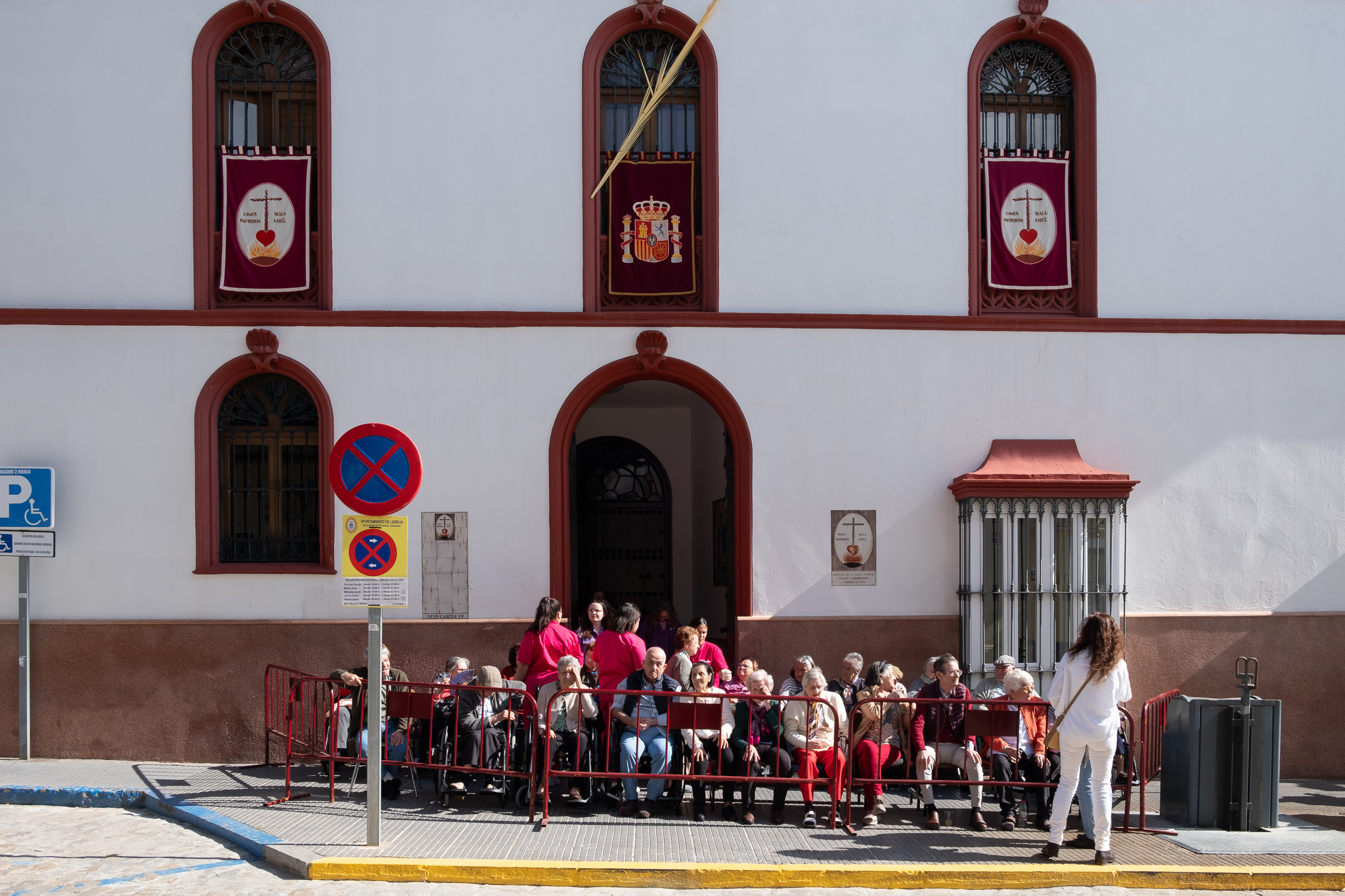 Senioren mit Palmzweig auf Sitzplätzen vor der Kirche